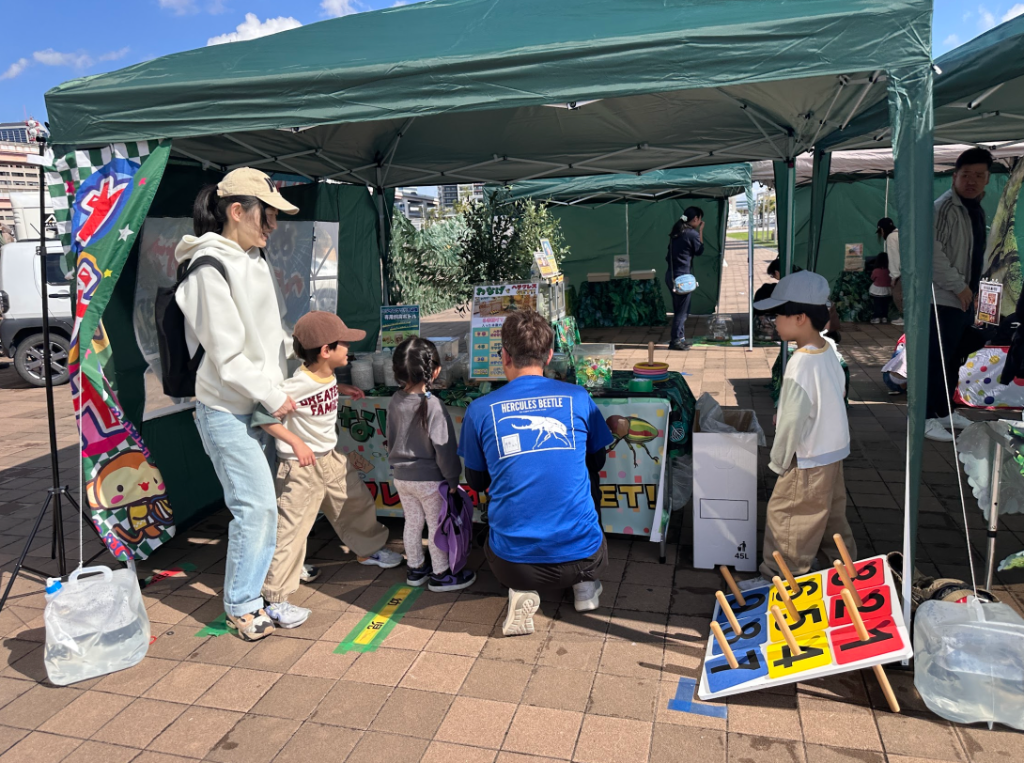 輪投げチャレンジブースでファミリーが体験する様子。スタッフは青いHERCULES BEETLE Tシャツを着用